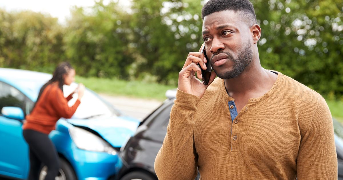 man on the phone at the scene of a car accident