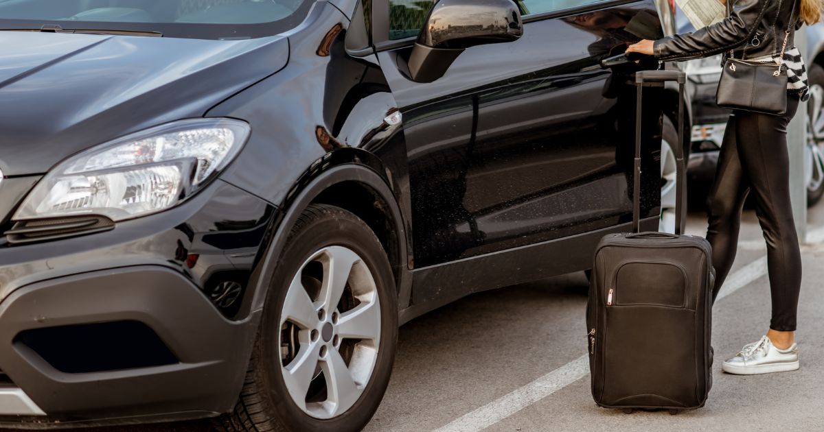 woman holding a suitcase getting into a rental car while on vacation